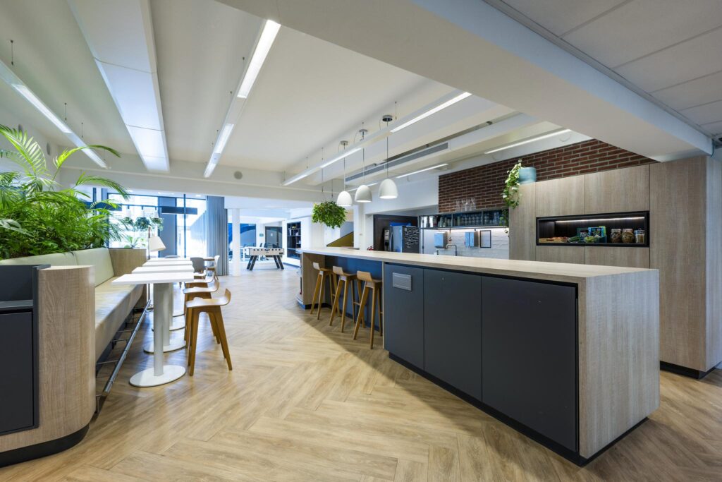 Modern office kitchen and lounge area on Mr. Treublaan with wooden finishes, bar seating, and greenery.